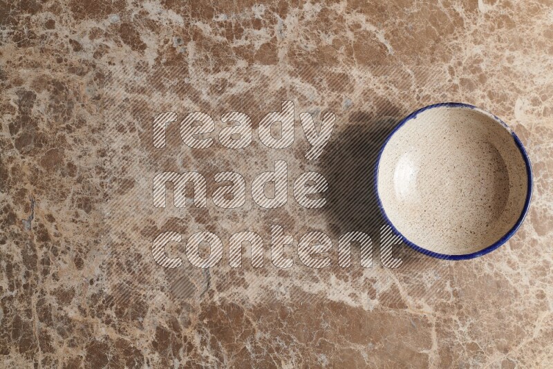 A multicolored pottery bowl on beige marble background