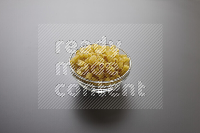 Big rings pasta in a glass bowl on grey background