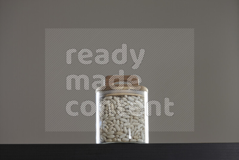 White beans in a glass jar on black background