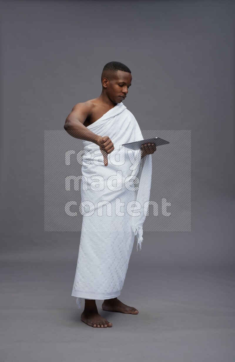 A man wearing Ehram Standing working on tablet on gray background