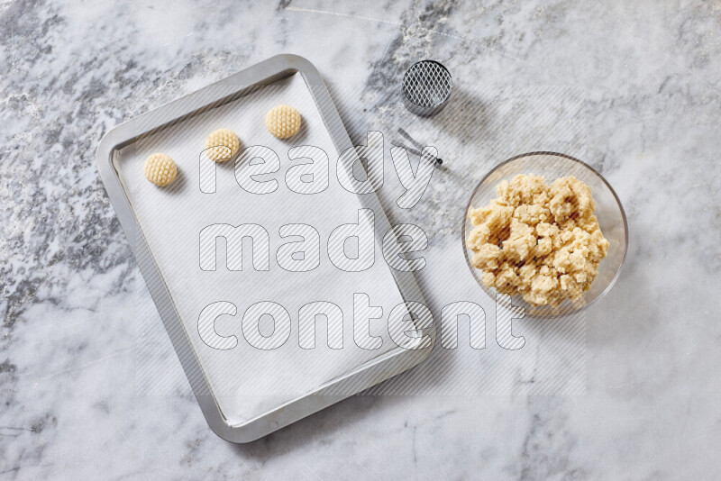 كحك خطوة بخطوة بمكوناته سمن، سكر، دقيق، سمسم، خميرة، ماء ونكهة الكحك على خلفية رخام رمادي