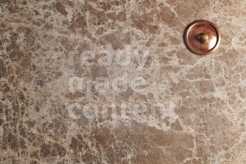 A small copper pot on beige marble background