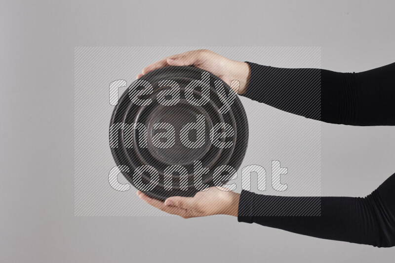 A woman in black abaya holding different pottery essentials in different positions