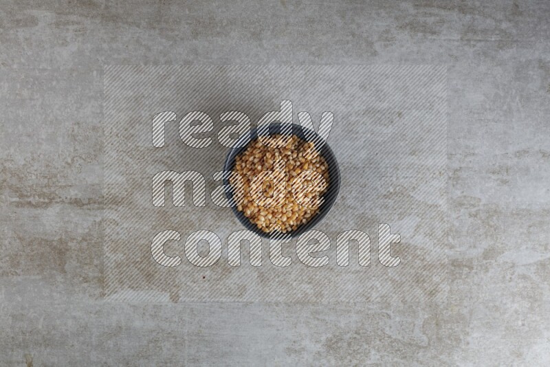 corn kernel in a black ceramic bowl on a grey textured countertop