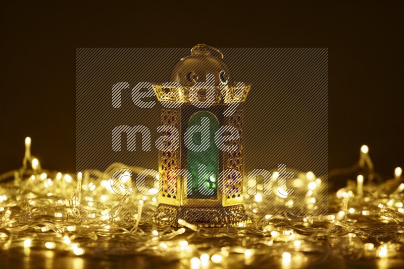A traditional ramadan lantern surrounded by glowing fairy lights in a dark setup