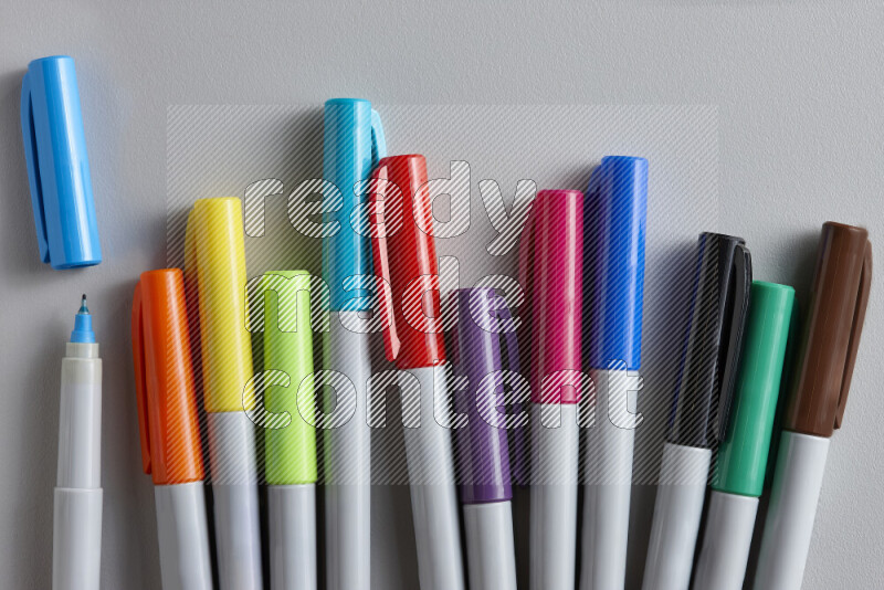 An arrangement of coloring pens in different colors on grey background