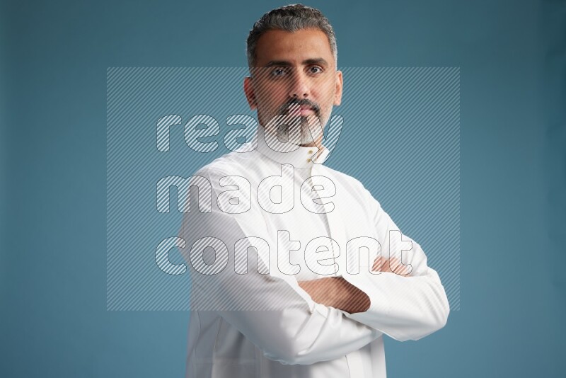 Saudi man waring thob posing to the camera on blue background