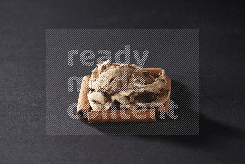 أربعة من أعواد القرفة مكونة شكل مربع بداخلها زنجبيل مجفف علي خلفية سوداء