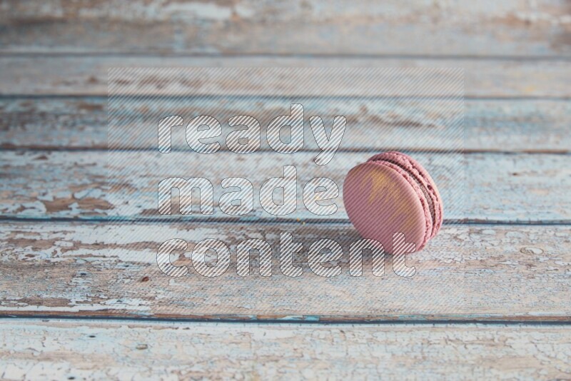 45º Shot of Purple Strawberry macaron on light blue wooden background