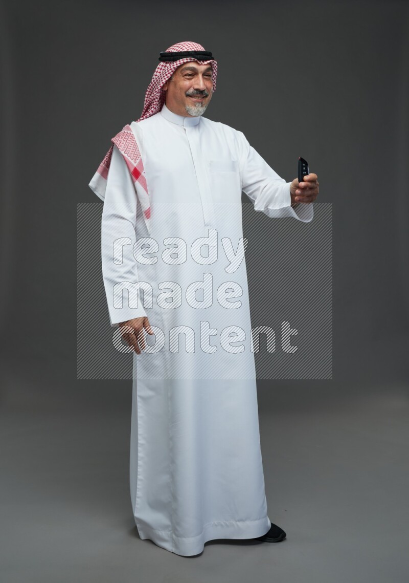 Saudi man with shomag Standing holding car key on gray background