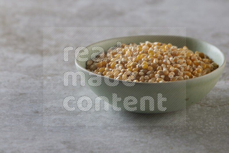 corn kernel in a green ceramic bowl on a grey textured countertop