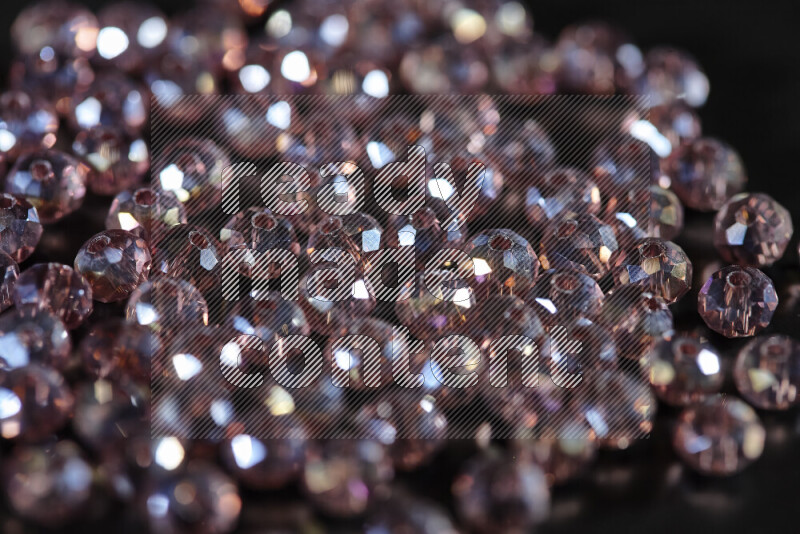 Rose transparent crystal beads scattered on a black background