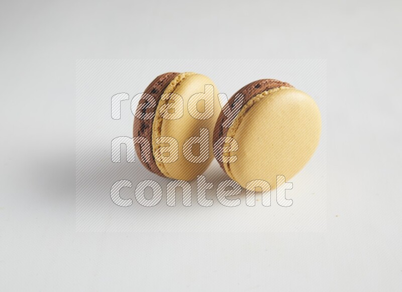 45º Shot of two Yellow and Brown Chai Latte macarons on white background