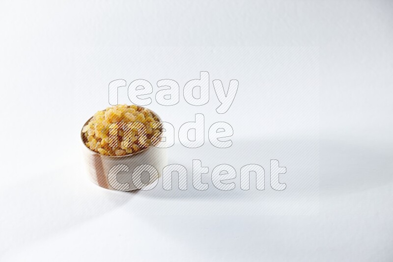 A beige ceramic bowl full of raisins on a white background in different angles