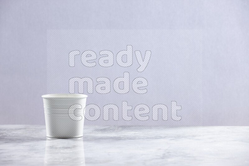 An empty white plant pot on grey marble background