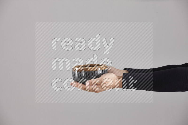 A woman in black abaya holding different pottery essentials in different positions