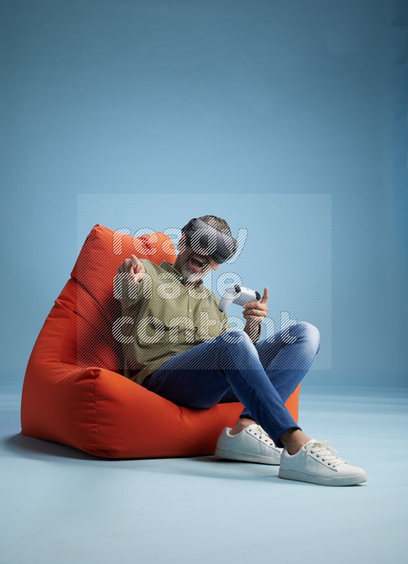 A man sitting on an orange beanbag and gaming with VR