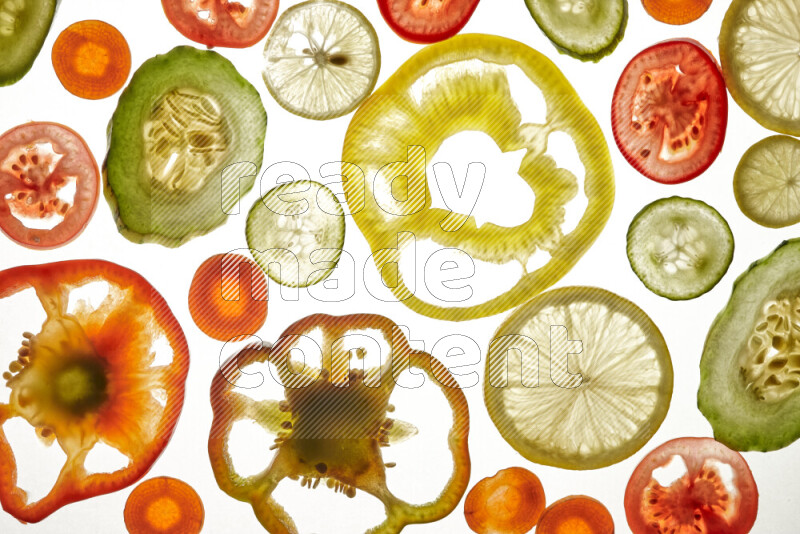 Mixed vegetables and fruits slices on illuminated white background