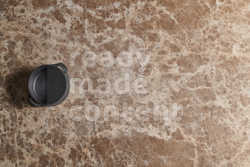 A black pottery bowl on beige marble background