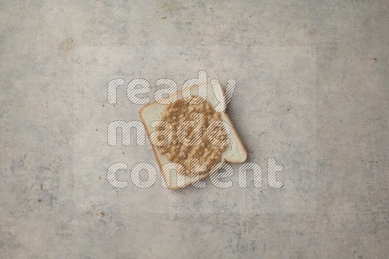 Crunchy peanut butter on a white toast on a light blue textured background