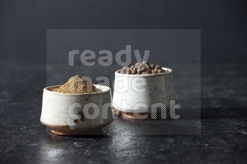 وعاءان بيج، أحدهما ممتلئ ببودرة بهار الفلفل الحلو والآخر بالحبوب على خلفية سوداء