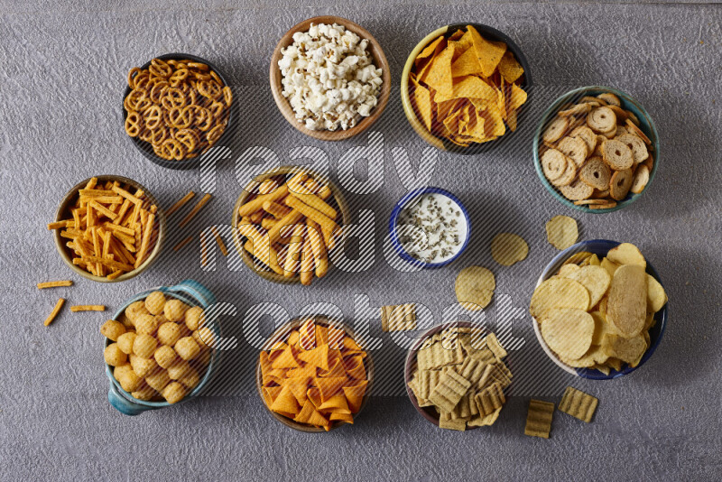 Assorted snacks in pottery bowls on grey background