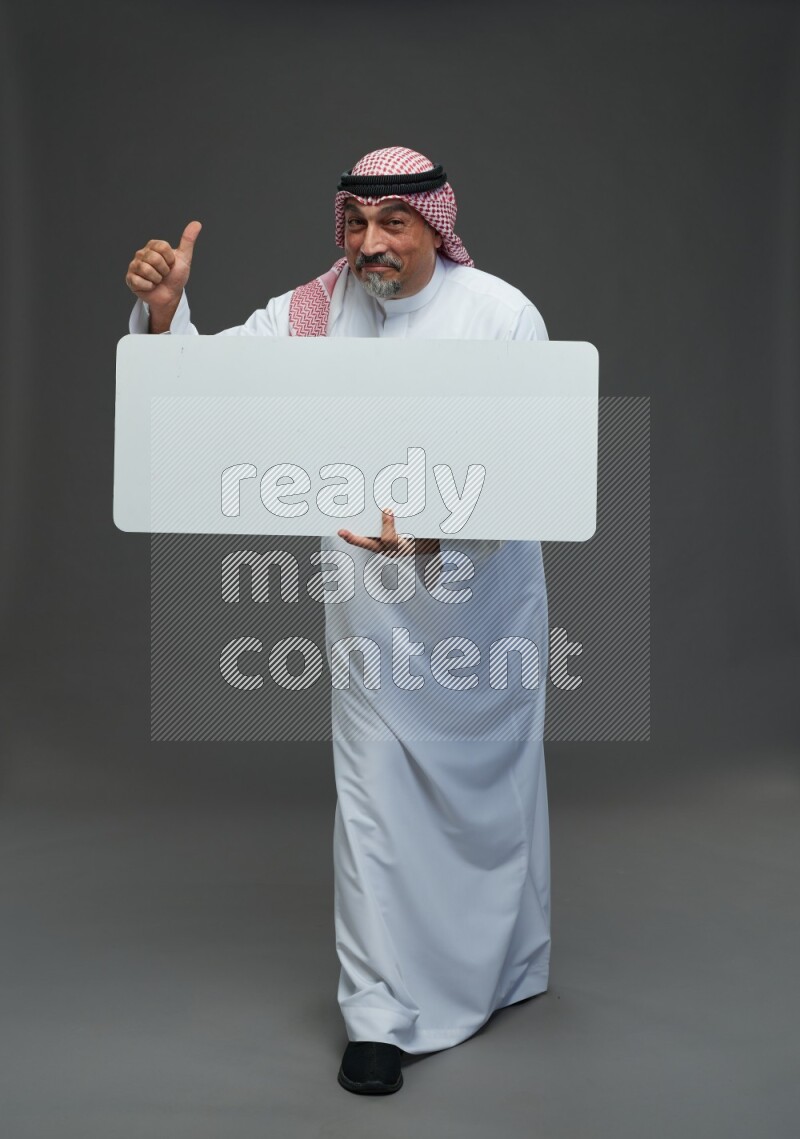 Saudi man with shomag Standing holding social media sing on gray background
