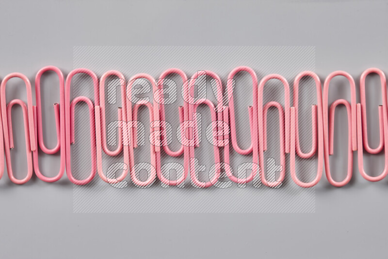 Pink paper clips isolated on a grey background