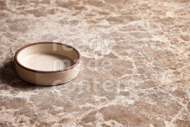 A beige pottery oven plate on beige marble background