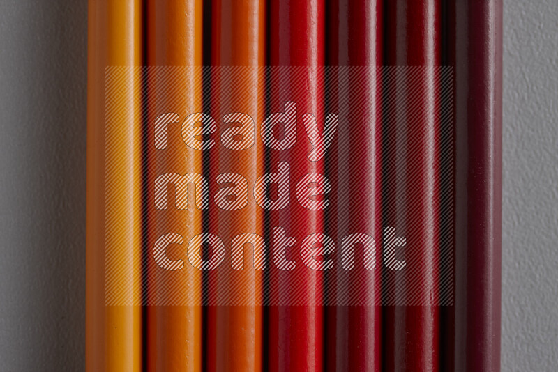 A collection of colored pencils arranged showcasing a gradient of orange and red hues on grey background