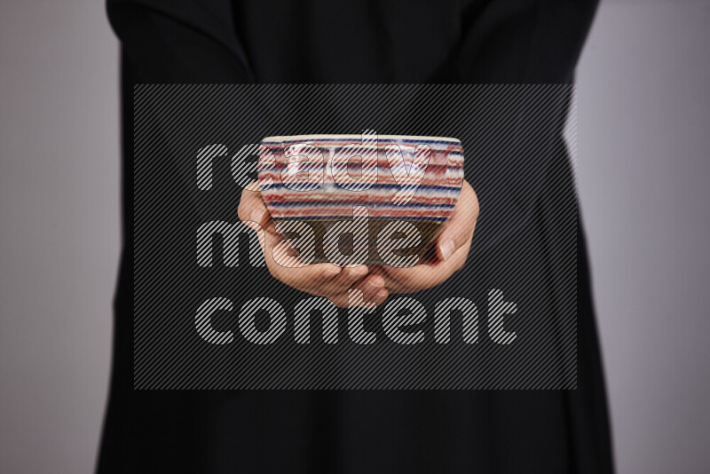 A woman in black abaya holding different pottery essentials in different positions