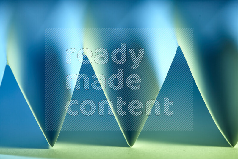 صورة مجردة مقربة تظهر طيات ورقية هندسية حادة بتدرجات اللون الأخضر والأزرق