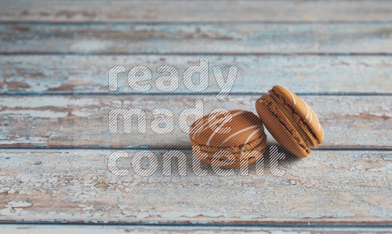 45º Shot of two Brown Irish Cream macarons on a  light blue wooden background