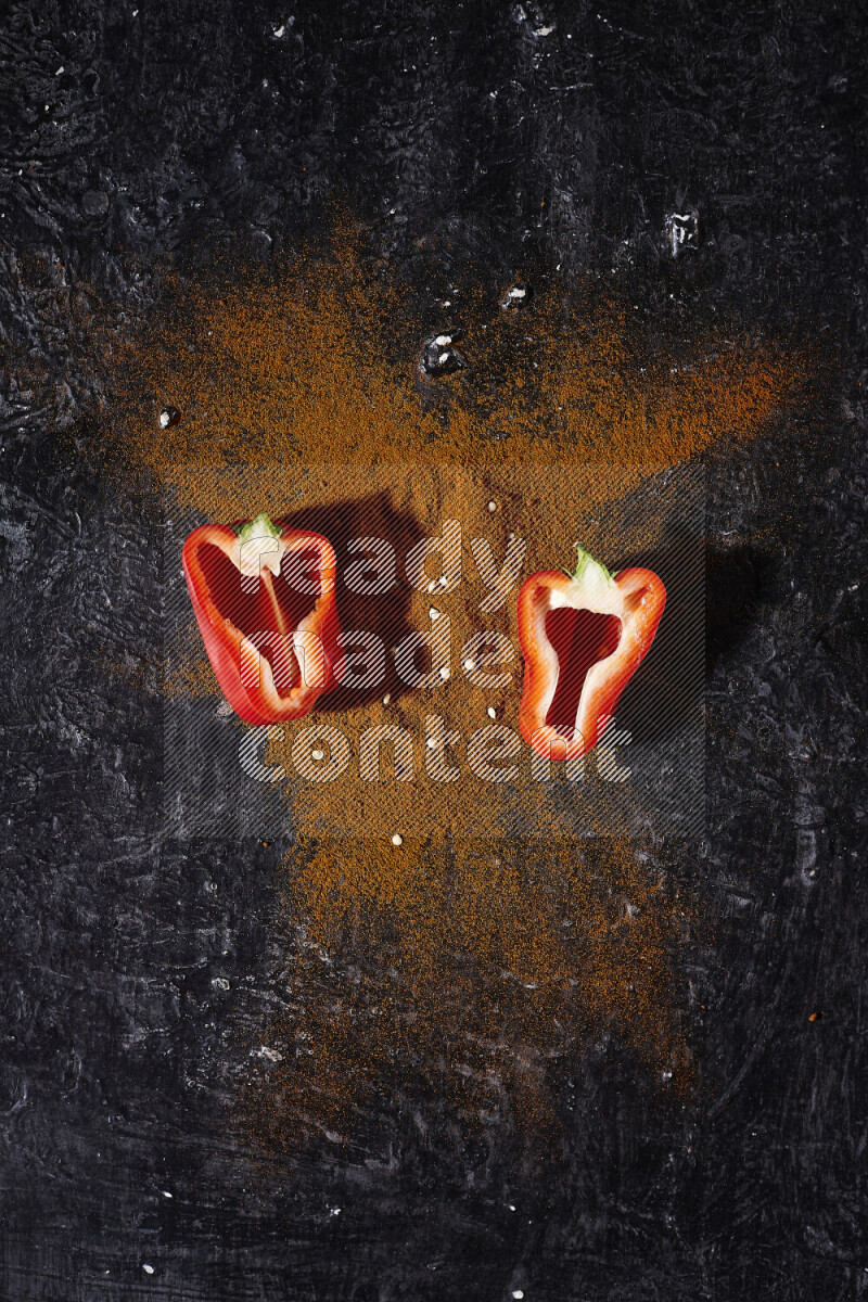 حفنة من بودرة البابريكا مع نصفين من الفلفل الأحمر الحلو على خلفية سوداء