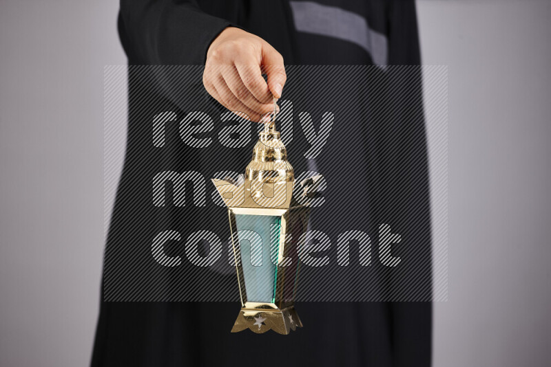 A woman in black abaya holding different ramadan lanterns in different positions