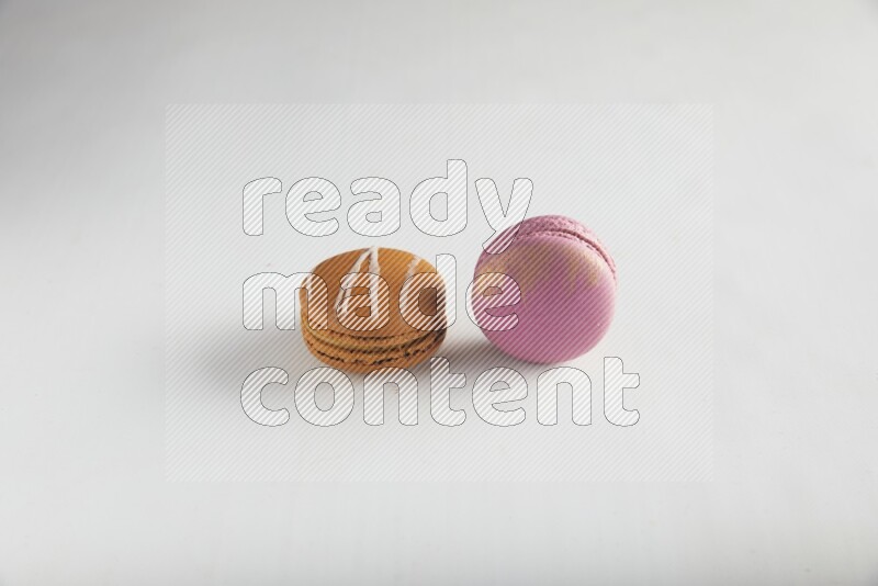 45º Shot of of two assorted Brown Irish Cream, and Purple Strawberry macarons on white background
