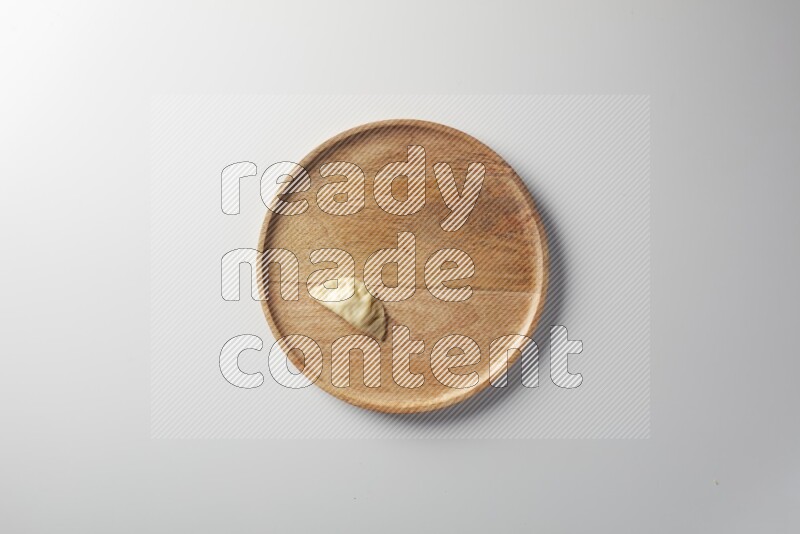 A single Sambosa on a wooden round plate on a white background
