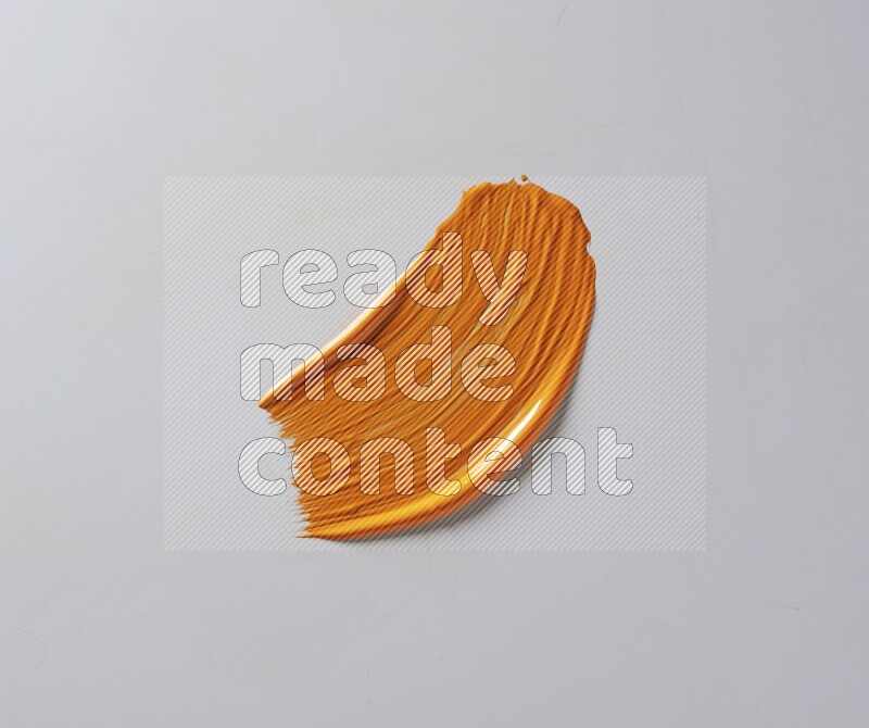 An orange curved painting brush stroke on a white background