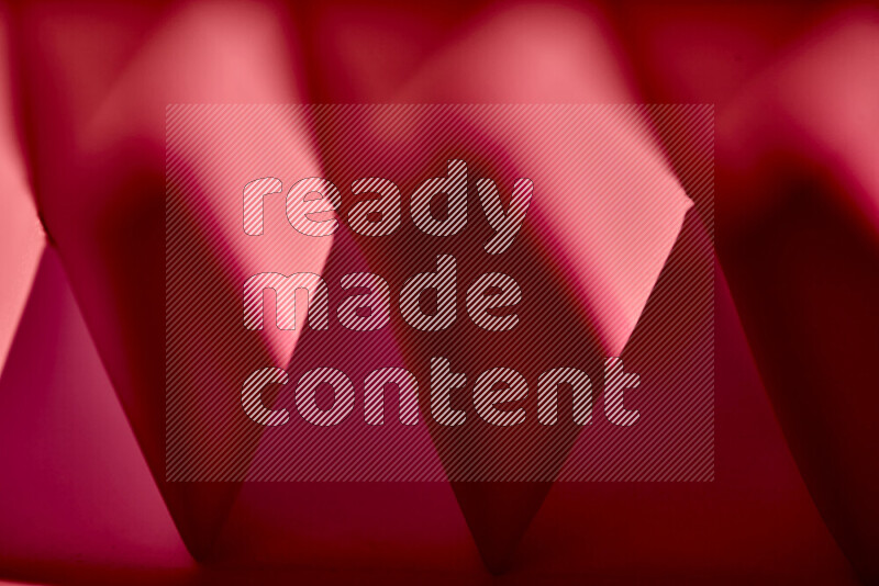 A close-up abstract image showing sharp geometric paper folds in red gradients