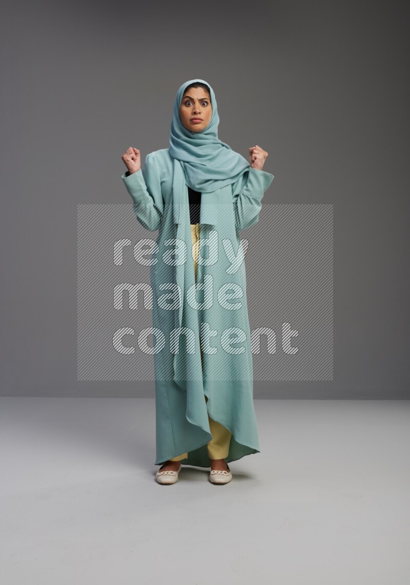 Saudi Woman wearing Abaya standing interacting with the camera on Gray background
