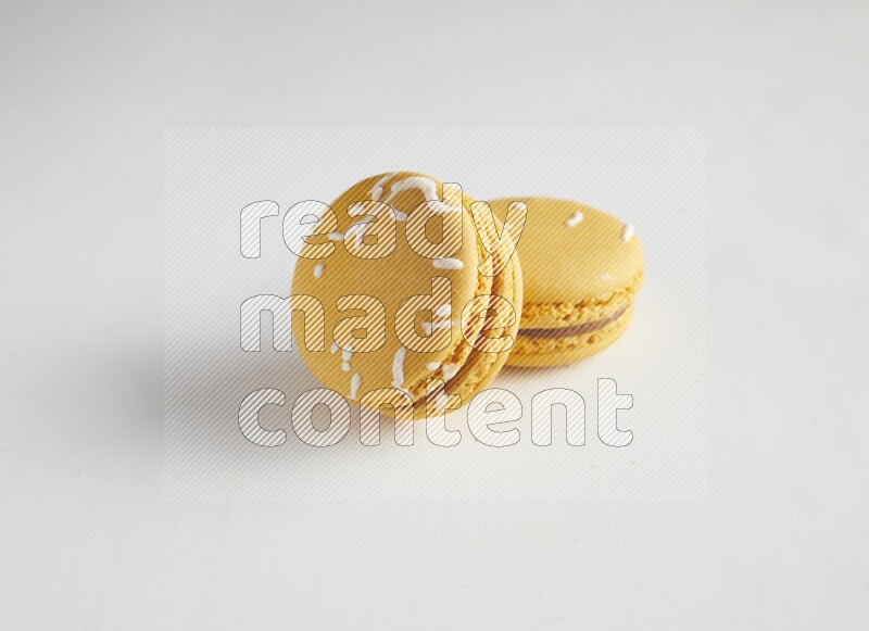45º Shot of two Yellow Piña Colada macarons on white background