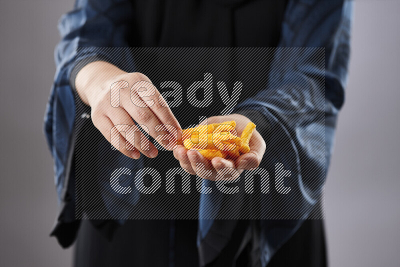 Woman in abaya holding different kinds of snacks in different positions
