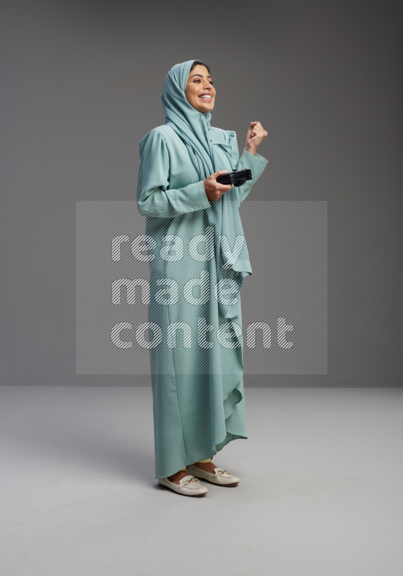 Saudi Woman wearing Abaya standing Playing Games on Gray background