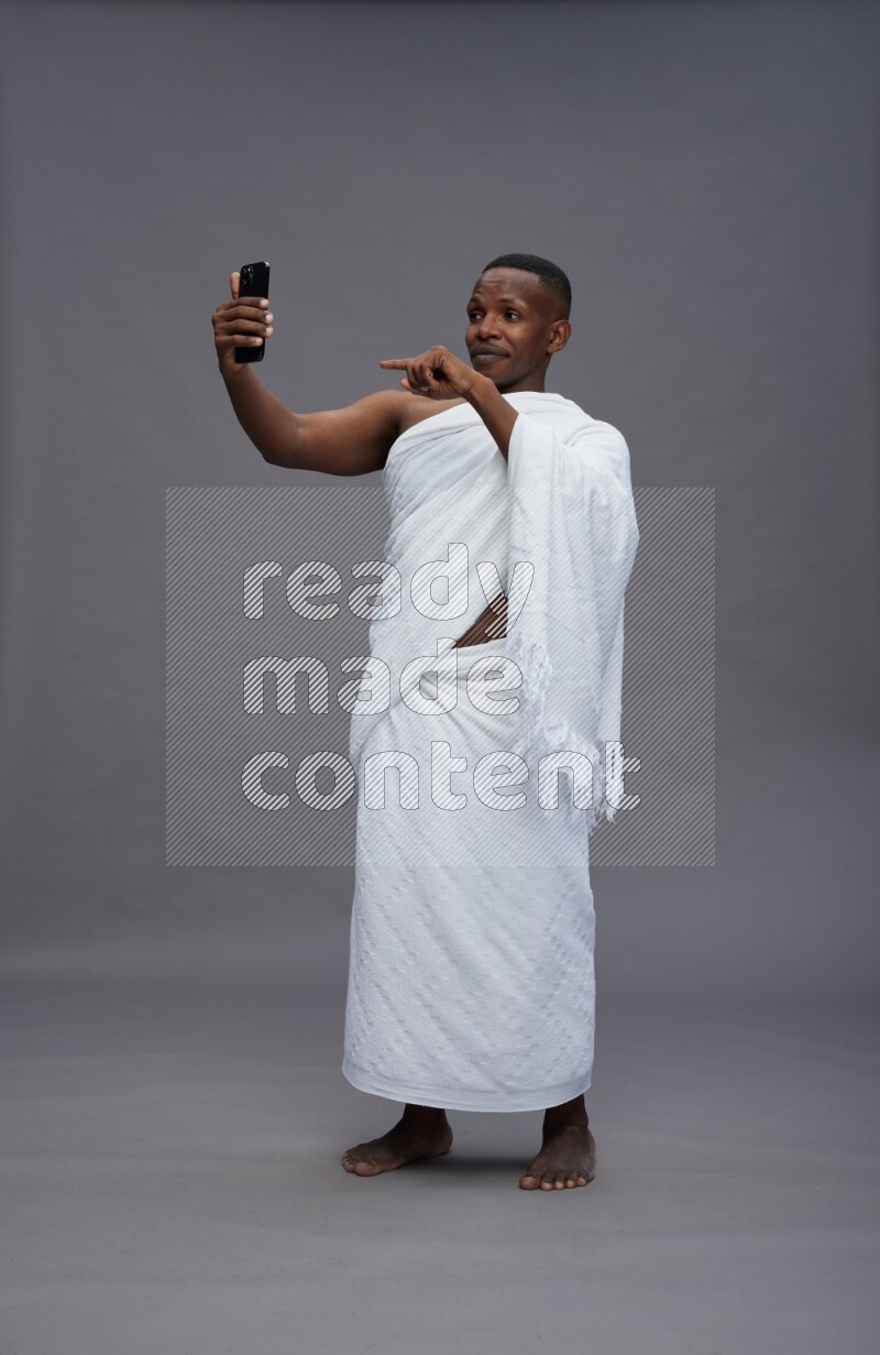 A man wearing Ehram Standing taking selfie on gray background