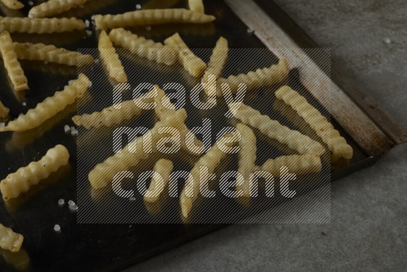 crinkle fries in a black stainless steel rectangle tray on grey textured counter top