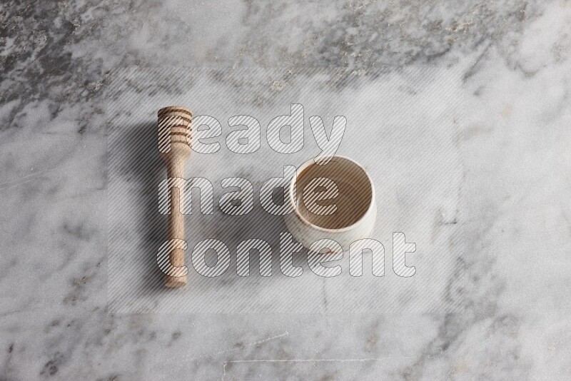 Decorative pottery bowl with wooden honey dipper on the side on grey marble background