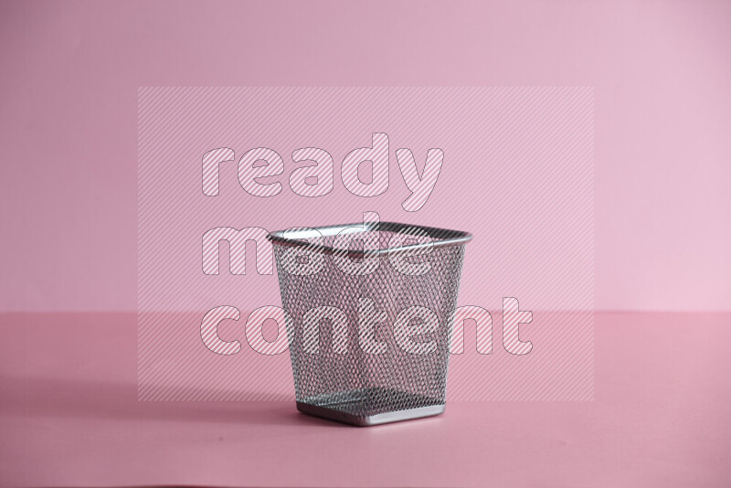 Pens, pencils and other different school supplies in a metal pen holder on rose background