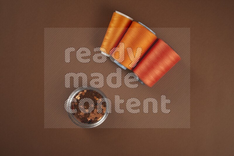 An orange collection of sewing and tailoring tools arranged on a brown background