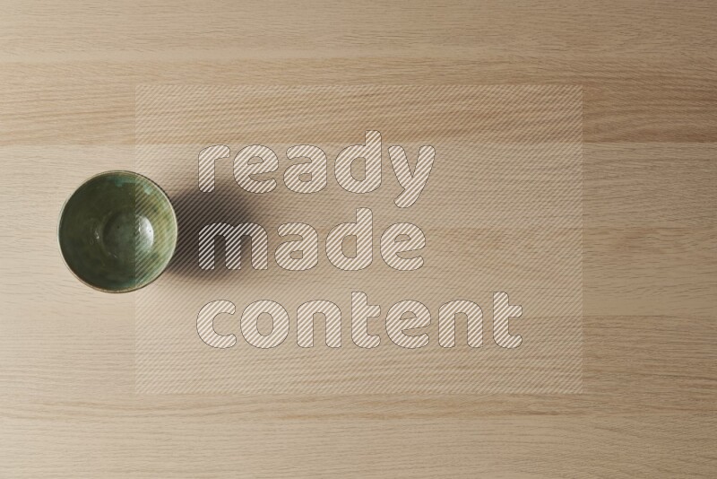 A dark green pottery bowl on light wooden background