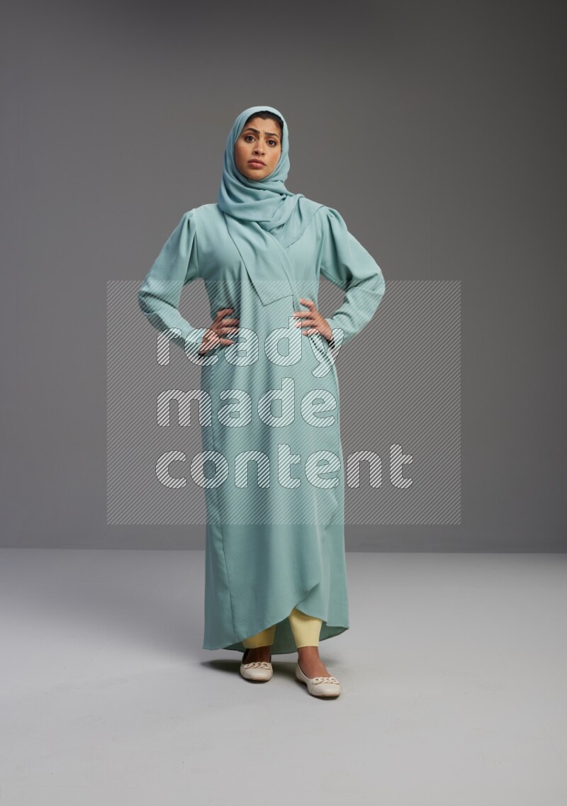 Saudi Woman wearing Abaya standing interacting with the camera on Gray background